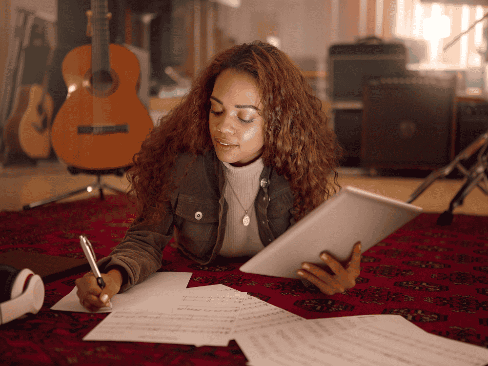 A lady musician scribbling lyrics and recording new melody to her wireless microphone